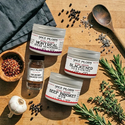 Spice Pilgrim seasoning containers on a wooden surface with herbs and spices.