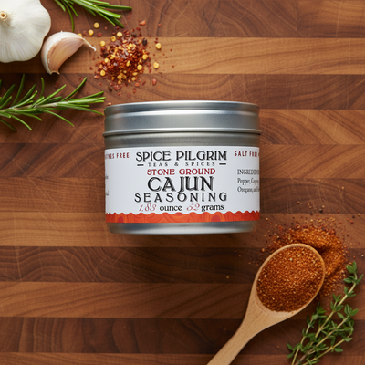 Spice Pilgrim Cajun seasoning canister on a wooden surface with herbs and spices.