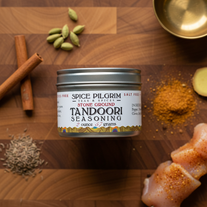 Tandoori seasoning container on a wooden surface with spices and chicken.